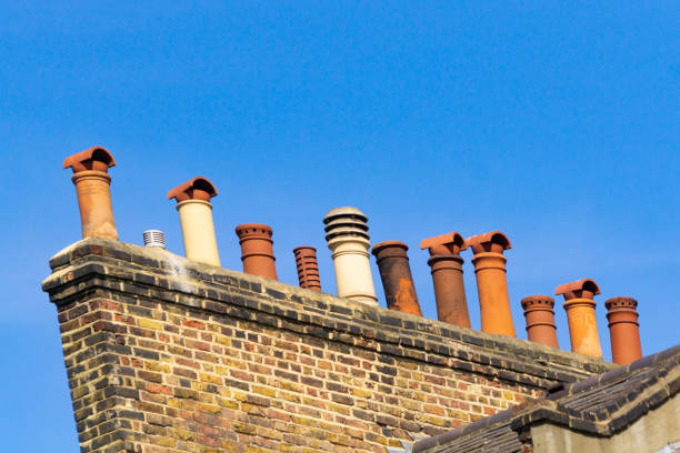 istock Row of several different style chimneys above roof tops 1202326182