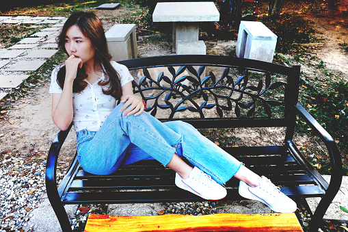 Young woman sitting in coffee shop at park bench.