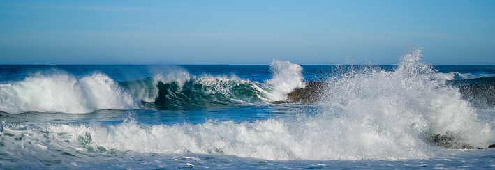 Grandes olas del océano chocan contra las piedras costeras en un día soleado photo