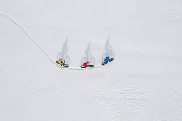 аэрофотосъемку группы друзей, катаясь на своем жирном велосипеде по снегу в онтарио, канада - transportation mountain winter couple стоковые фото и изображения