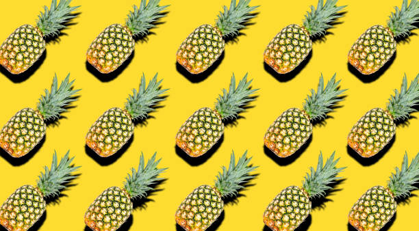 istock Creative pattern of fruit whole pineapples with shadows on a bright yellow summer background. Clipping Path. 1202333699