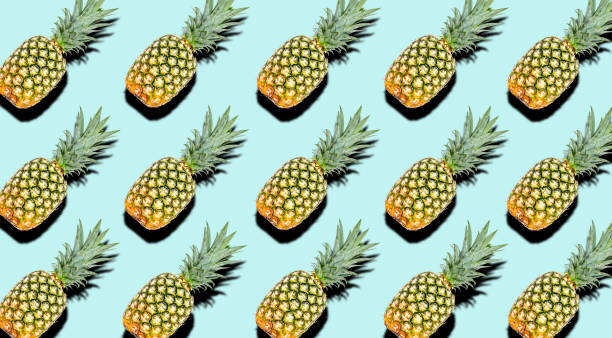 istock Creative pattern of fruit whole pineapples with shadows on a soft blue summer background. Clipping Path. 1202333750