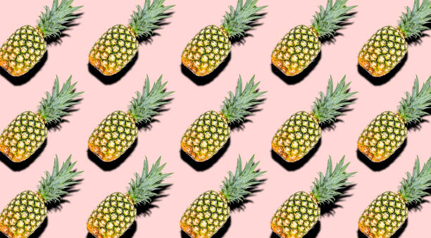 istock Creative pattern of fruit whole pineapples with shadows on a soft pink color summer background. Clipping Path. 1202333796