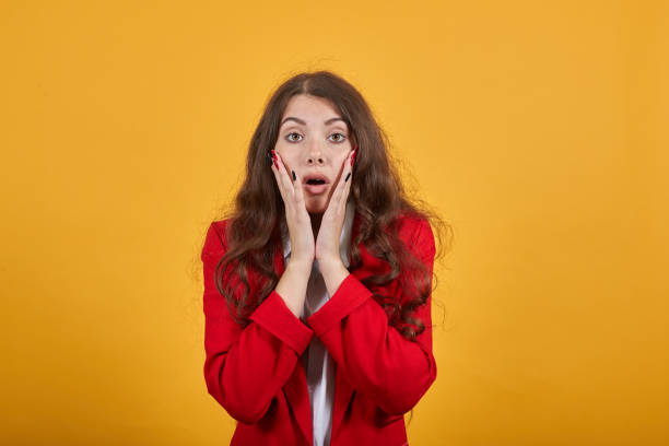 istock Surprised lady in shirt and jacket keeping mouth opened, holding hands on cheeks 1202339713