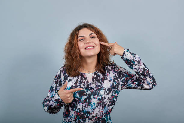 istock Cheerful caucasian young woman pointing finger at cheeks, looking happe, smiling 1202341966