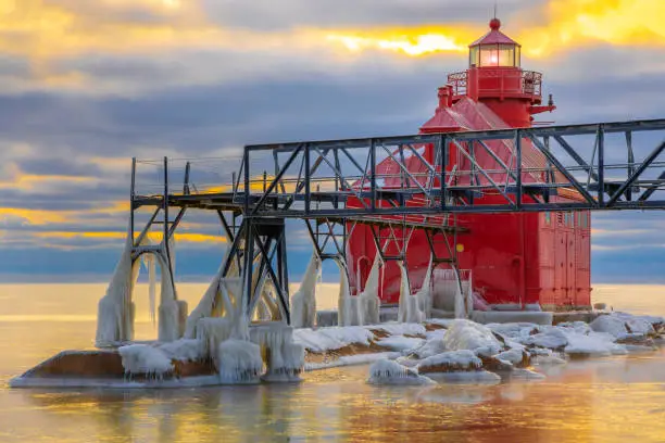 Winter ice buildup on scenic pier and lighthouse, photographed at sunrise for some stunning views of what it means to be cold.