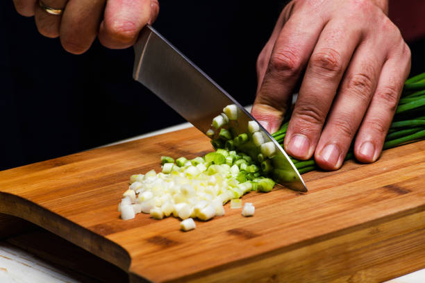 istock Cooking. Chef is cutting green onion in the kitchen 1202342158