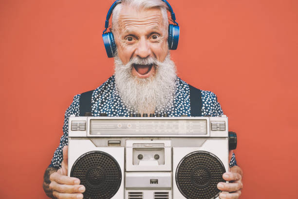 glücklicher senior mann hören musik mit boombox und kopfhörer im freien - crazy hipster männlich spaß mit vintage stereo - konzept der älteren menschen lebensstil - bizarre making a face men one person stock-fotos und bilder