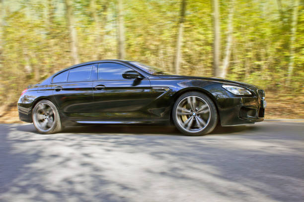 Black BMW M6 in autumn forest. BMW in motion stock photo