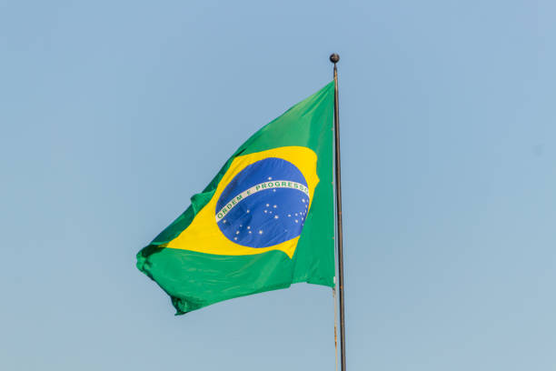 istock Brazilian flag flying with blue sky background 1202343527