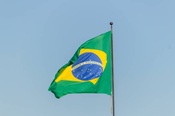 istock Brazilian flag flying with blue sky background 1202343875