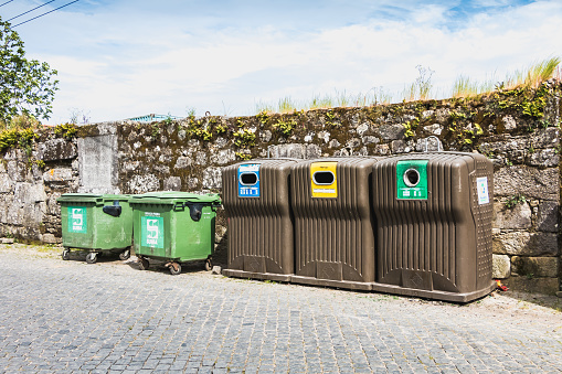 Vila Cha near Esposende, Portugal - May 9, 2018: Public recycling bins in front of a stone wall in the city center on a spring day