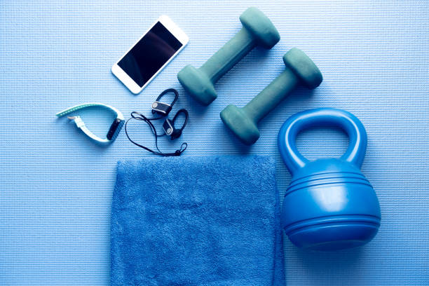 equipos de fitness y electrónica en una estera de yoga azul - foto de stock