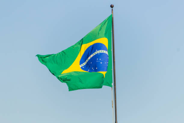 istock Brazilian flag flying with blue sky background 1202346005