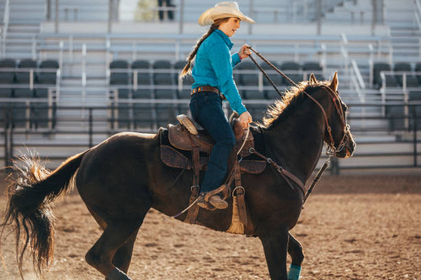 на родео основания, подростковой cowgirl тянет вожжи, чтобы остановить лошадь, как только баррель гоночных конкуренции закончилась. - одна девушка только стоковые фото и изображения