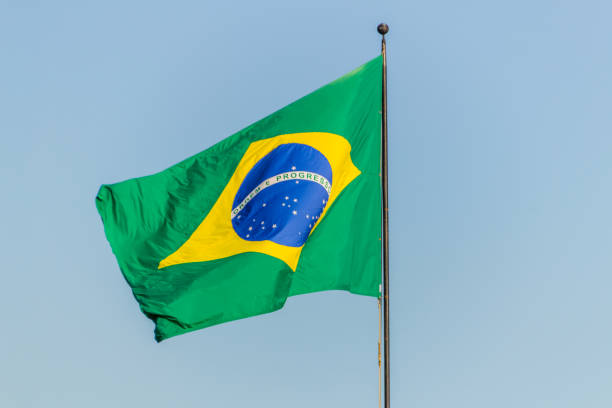 istock Brazilian flag flying with blue sky background 1202347149