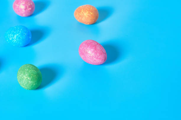 istock Many scattered colorful eggs with glitters lies on blue table on kitchen. Easter concept. Space for text 1202348679
