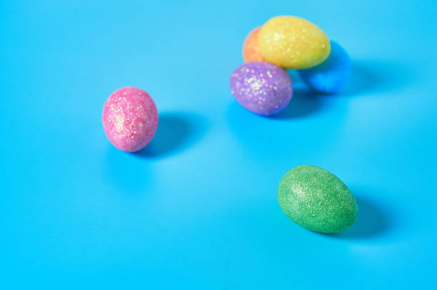istock Many scattered colorful eggs with glitters lies on blue table on kitchen. Easter concept. Close-up 1202348697