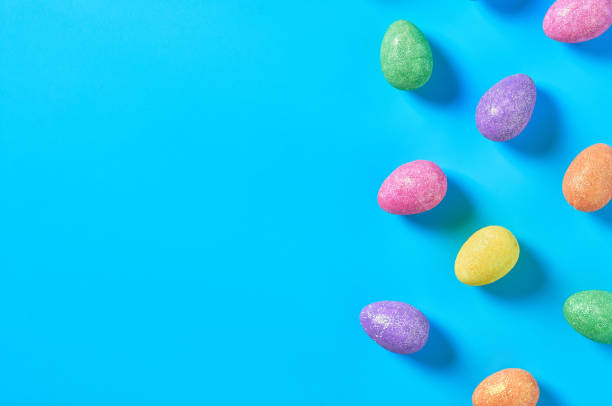istock Many scattered colorful eggs with glitters lies on blue table on kitchen. Easter concept. Space for text. Top view 1202348698