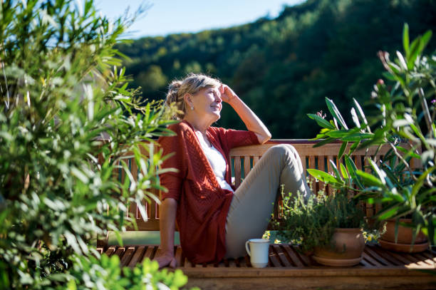 istock Senior woman with coffee sitting outdoors on terrace, resting. 1202351289