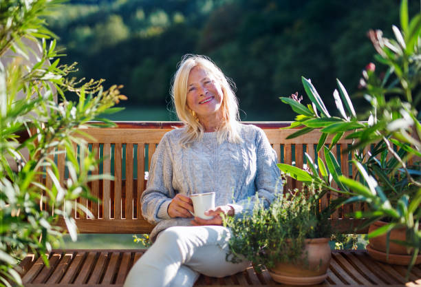 istock Senior woman with coffee sitting outdoors on terrace, resting. 1202351300