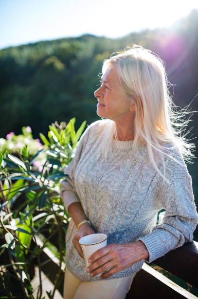 istock Senior woman with coffee standing outdoors on terrace, resting. 1202351310