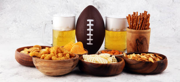 istock Chips, salty snacks, football and Beer on a table. Great for Bowl Game snack projects. 1202351372