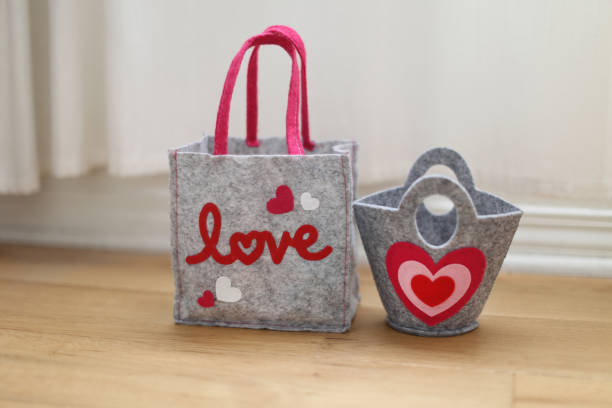a cute small grey felt bag and a basket with heart on a hardwood floor in a room