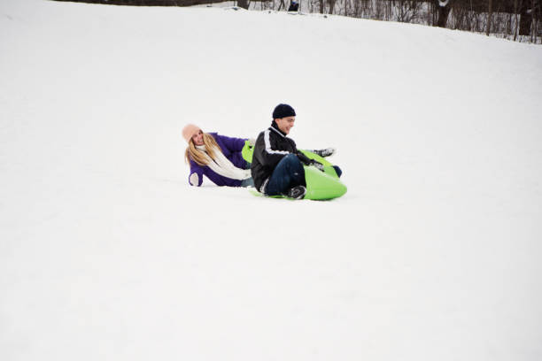 istock Generation Z couple sliding down in snowy public park. 1202352464