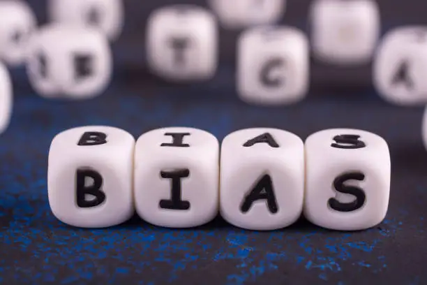 Bias - word from white blocks with black letters, personal opinions prejudice bias concept, random letters around.