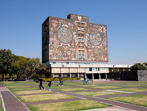 Mexico City, Mexico, January 8, 2020. Mexico city University campus library iconic facade  created by the Mexican artist Juan O'Gorman with people walking by