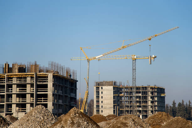 istock Tower crane lifts the block for building under construction at background blue sky 1202354846