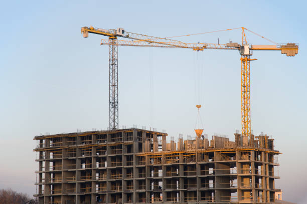 istock Tower cranes constructing a new residential building at a construction site against blue sky 1202355946