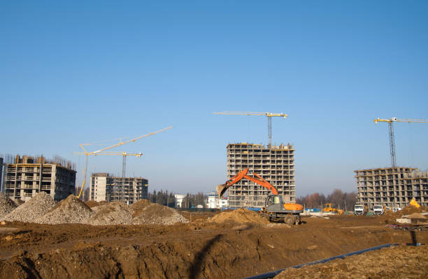 istock Excavator digs ground at a construction site for installing concrete storm pipes 1202356028