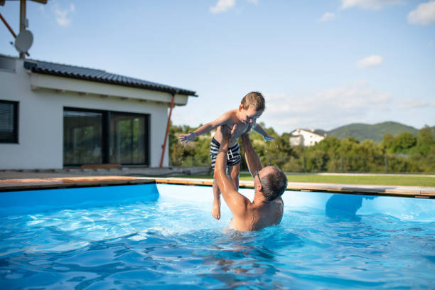 istock A father with small son playing in swimming pool outdoors. 1202356054