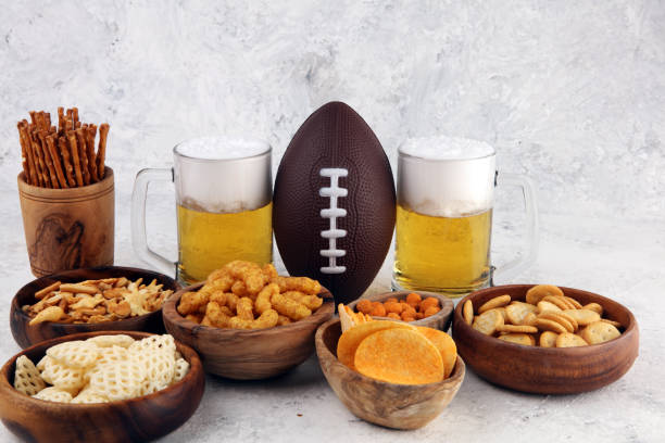 istock Chips, salty snacks, football and Beer on a table. Great for Bowl Game snack projects. 1202356198