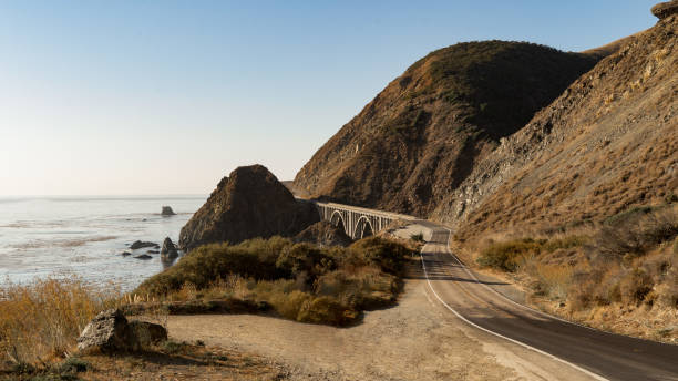 istock Road curving along Pacific Coast towards a bridge 1202358711