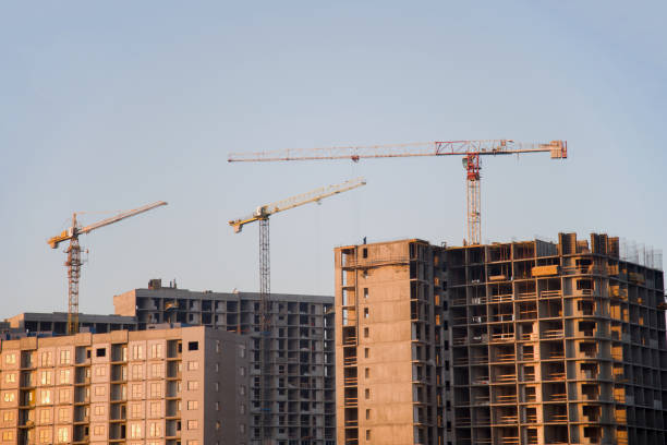 istock Tower cranes constructing a new residential building at a construction site against blue sky 1202359262