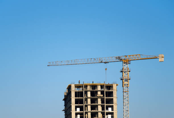 istock Tower crane constructing a new residential building at a construction site against blue sky 1202359348
