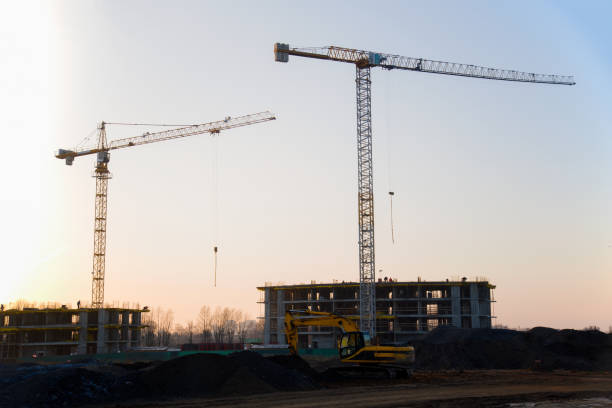 istock Tower cranes constructing a new residential building at a construction site against blue sky 1202359401