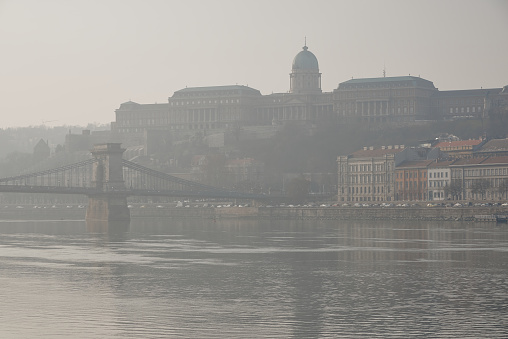 The foggy morning of the old town of Budapest. View of Buda Castle and Chain Bridge at distance. Danube river. Hungary. Top tourist attractions in Europe.