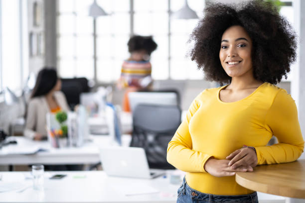 istock African woman in yellow outfit leaning on table 1202365601