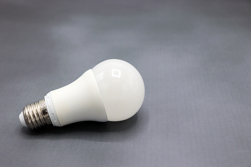 White LED smart light bulb isolated on grey background with Edison screw connector