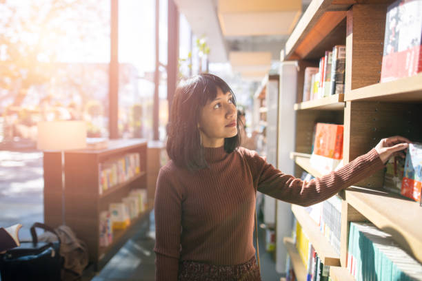 istock Asian woman looking for books at library 1202369334