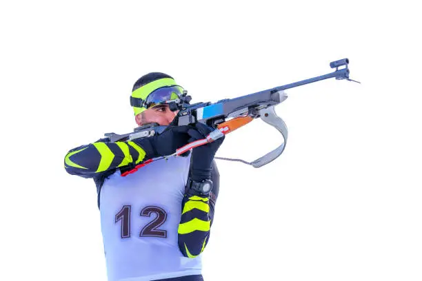 Isolated biathlete in standing position with rifle. Aimed the target