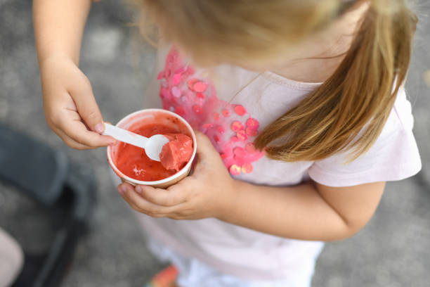 istock Girl eats pink ice cream. View from above 1202373997