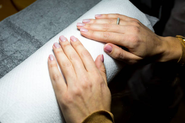 Closeup of nicely manicured female fingernails. Very nice french manicure with transparent nail paint. Blurry beige background. Copy space
