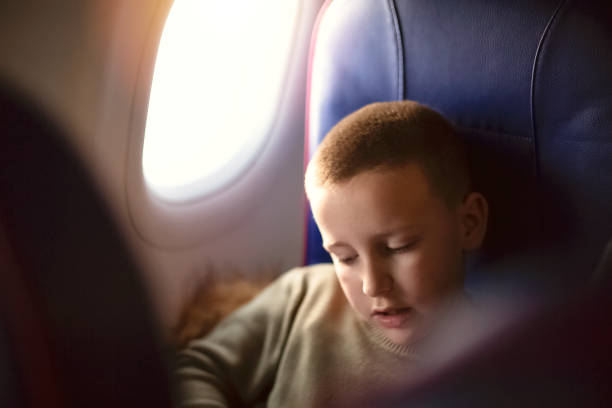 istock Boy in airplane sitting in a window seat and enjoying 1202382209