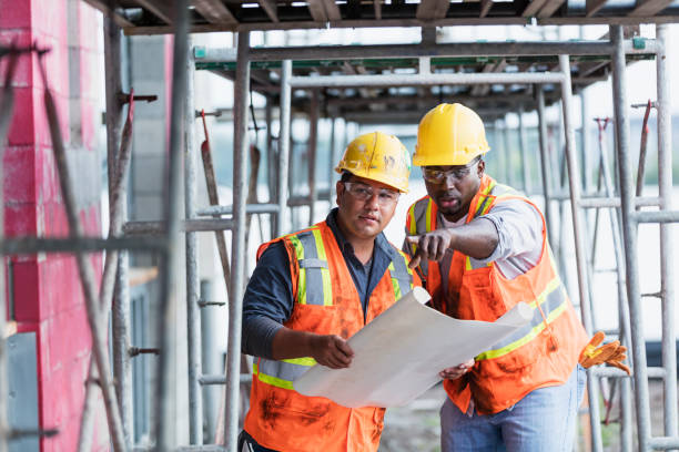 pracownicy na placu budowy przyglądający się planom, wskazując - foreman building contractor hardhat men zdjęcia i obrazy z banku zdjęć