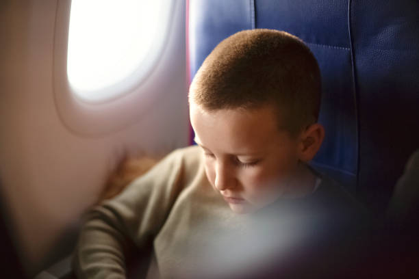 istock Boy in airplane sitting in a window seat and enjoying 1202382237